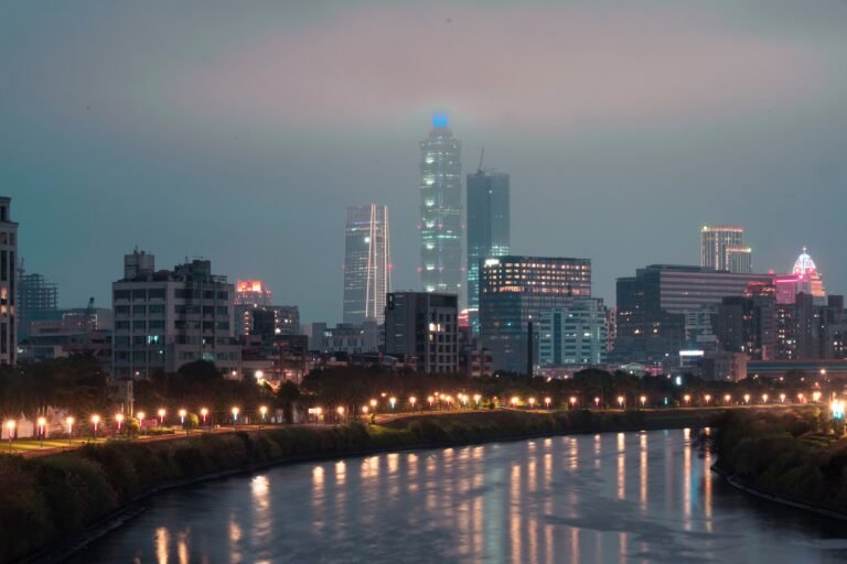 Majestic city skyline along the river, glowing with vibrant lights during nighttime.